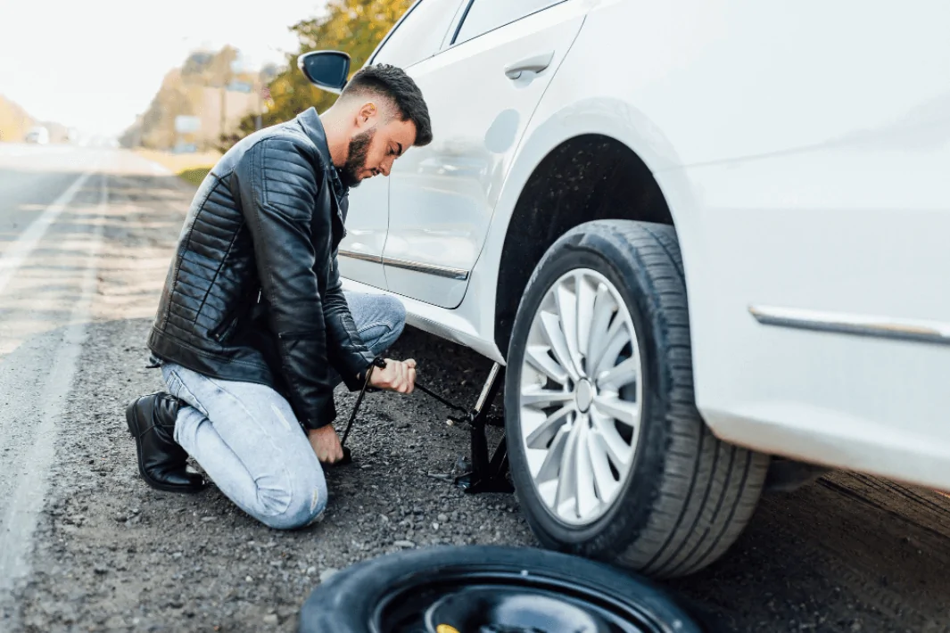 barbaat in geaca de piele care repara roata la masina perne auxiliare air power